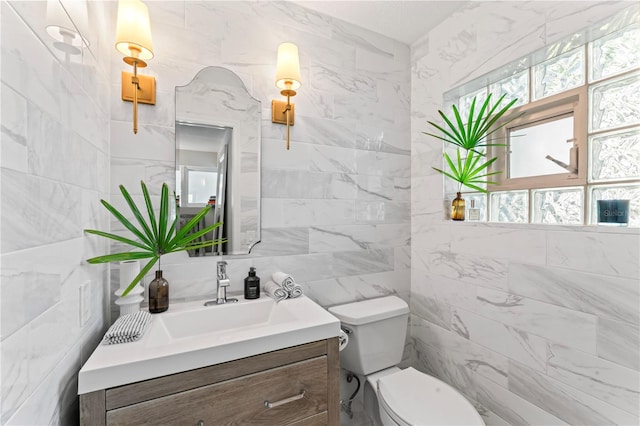 bathroom featuring toilet, tile walls, vanity, and a healthy amount of sunlight