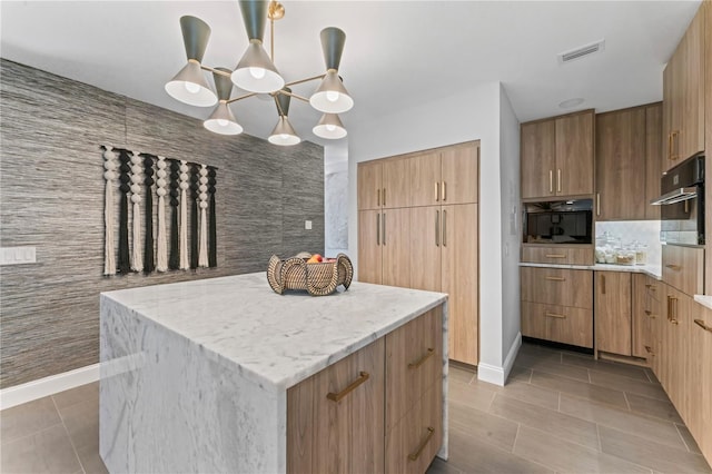 kitchen with light stone counters, light tile patterned floors, a kitchen island, visible vents, and stainless steel oven