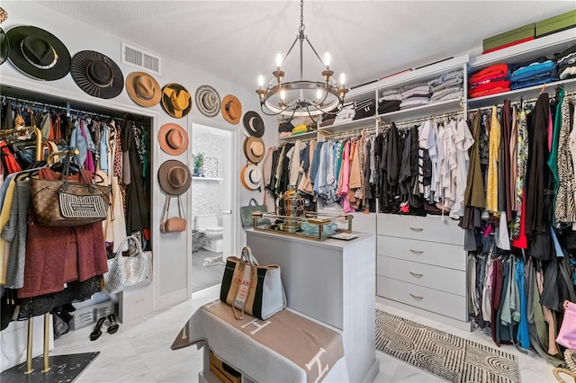 walk in closet with a notable chandelier, visible vents, and marble finish floor