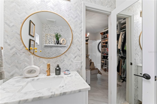 bathroom with a walk in closet and vanity