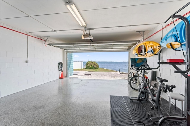 garage featuring a water view, a garage door opener, and concrete block wall