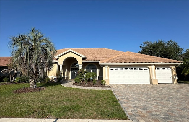 view of front of property featuring stucco siding, a front lawn, a tile roof, an attached garage, and driveway
