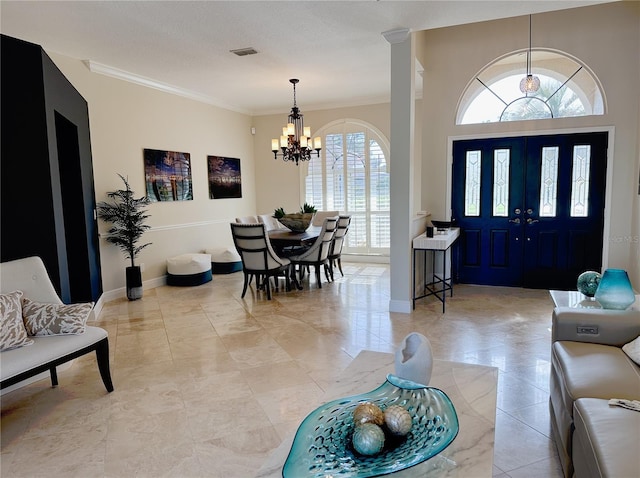 entrance foyer featuring a notable chandelier, baseboards, ornamental molding, and visible vents