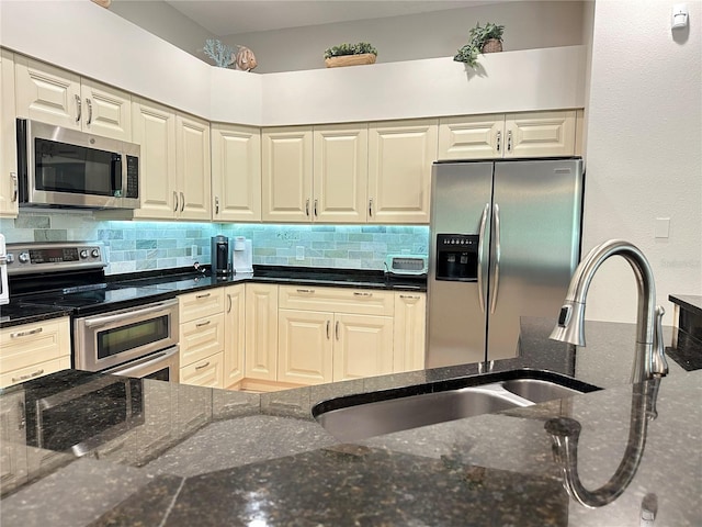 kitchen with tasteful backsplash, a sink, dark stone counters, and appliances with stainless steel finishes