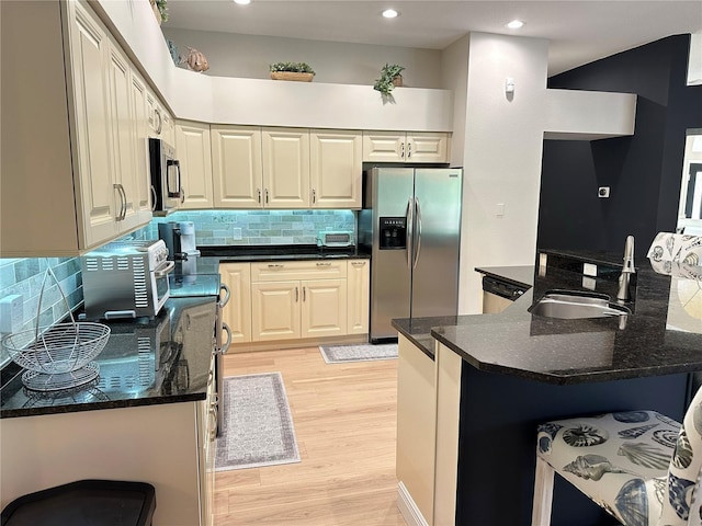 kitchen with tasteful backsplash, light wood finished floors, a sink, and stainless steel appliances