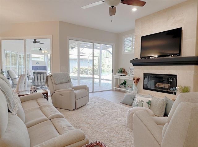 living room with wood finished floors, ceiling fan, a fireplace, and recessed lighting