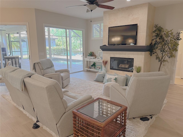 living room featuring a premium fireplace, a ceiling fan, and wood finished floors