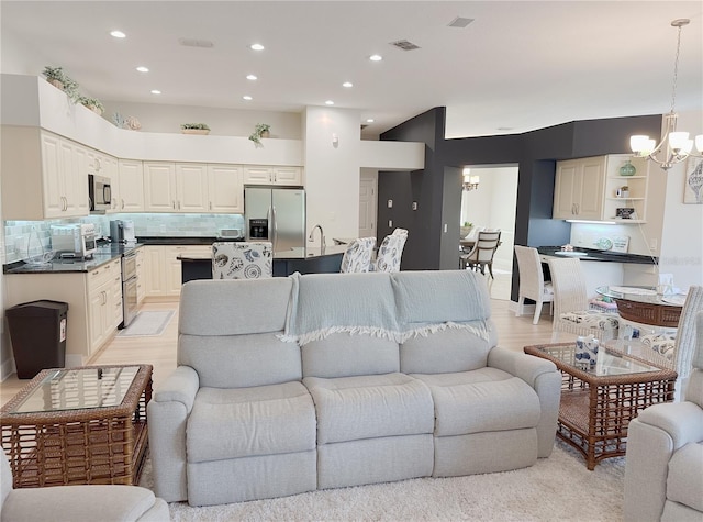 living room featuring recessed lighting, a notable chandelier, visible vents, and light wood-style flooring