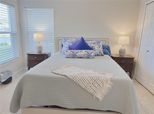 bedroom with a closet, light tile patterned floors, baseboards, and multiple windows