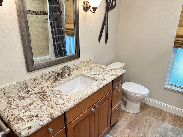 bathroom with toilet, a shower with shower curtain, vanity, and baseboards