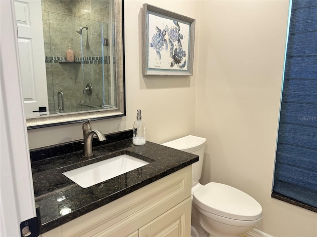 bathroom featuring toilet, a shower stall, and vanity