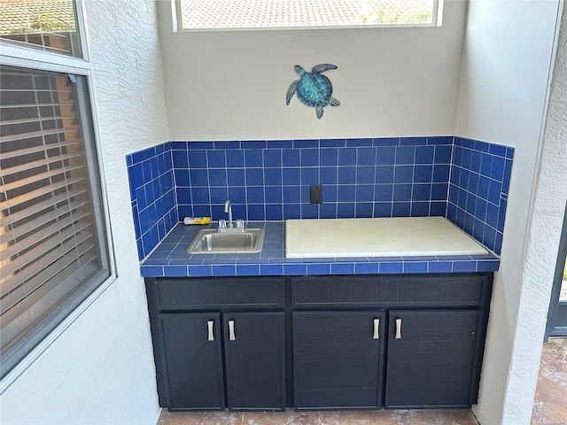 bathroom with a healthy amount of sunlight, a textured wall, and a sink