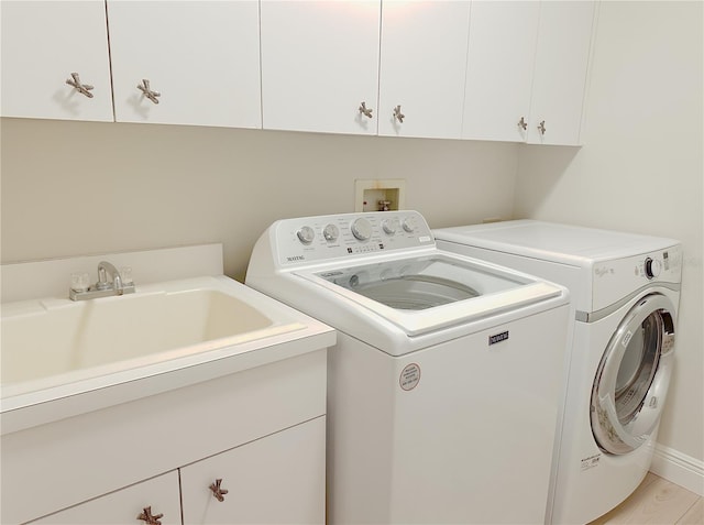 washroom featuring washer and dryer, light wood-type flooring, a sink, and cabinet space