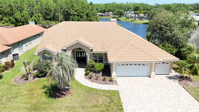 single story home with driveway, a front lawn, an attached garage, a tile roof, and a water view
