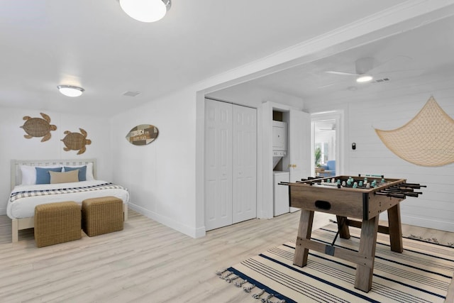 2215 Thrace St, Tampa, FL 33605 - recreation room featuring stacked washer and clothes dryer, light wood-style floors, baseboards, and a ceiling fan