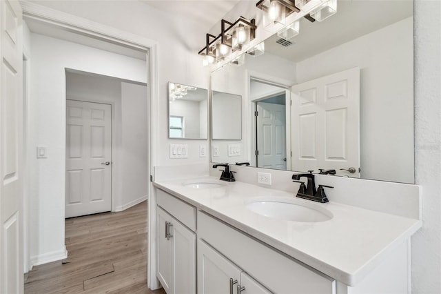 full bathroom with a chandelier, wood finished floors, visible vents, and a sink