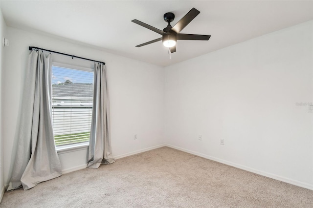 carpeted spare room with baseboards and a ceiling fan