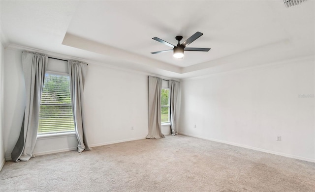 unfurnished room featuring visible vents, a raised ceiling, a healthy amount of sunlight, and carpet floors