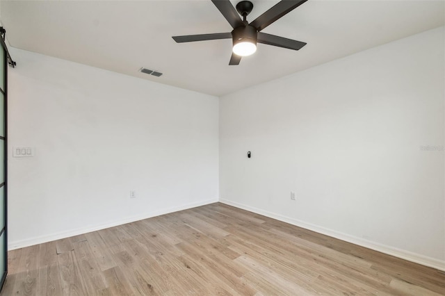 spare room featuring baseboards, ceiling fan, light wood-style flooring, and visible vents
