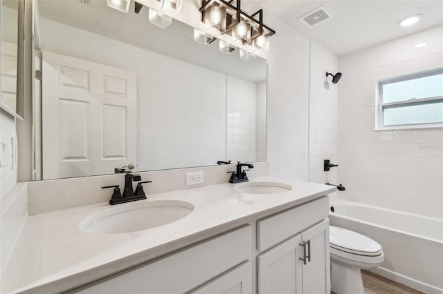 bathroom with toilet, visible vents, a sink, and double vanity