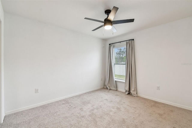 empty room with light colored carpet, baseboards, and a ceiling fan