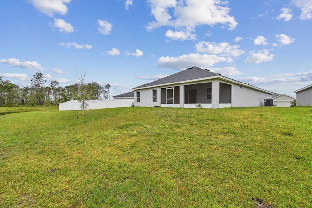 rear view of house featuring a yard and fence