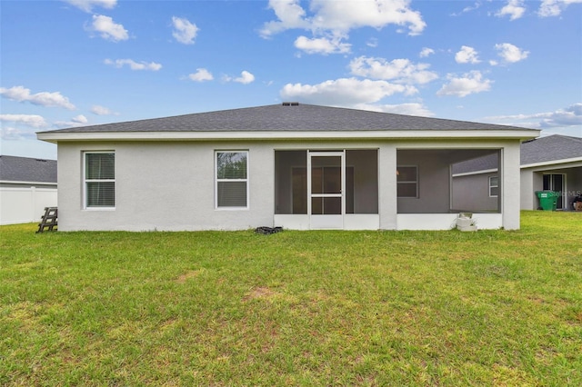 back of property with a sunroom, a shingled roof, stucco siding, and a lawn