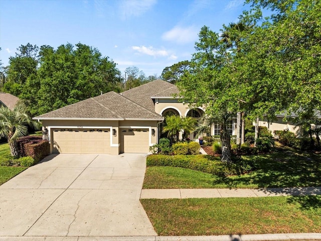 view of front of property featuring concrete driveway, stucco siding, a front lawn, a garage, and a shingled roof