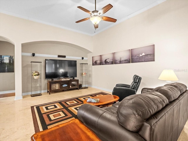 living area with arched walkways, ceiling fan, baseboards, and ornamental molding