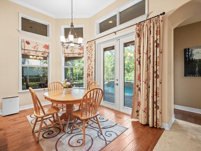 dining room featuring baseboards, a chandelier, french doors, crown molding, and hardwood / wood-style flooring