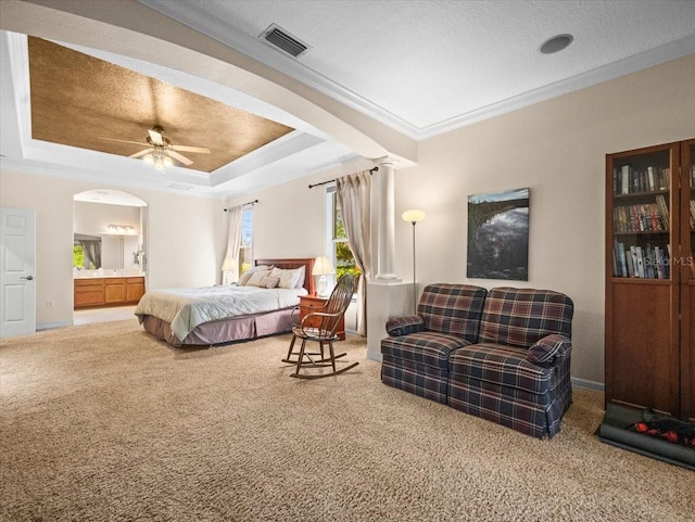 carpeted bedroom featuring a raised ceiling, crown molding, visible vents, and arched walkways