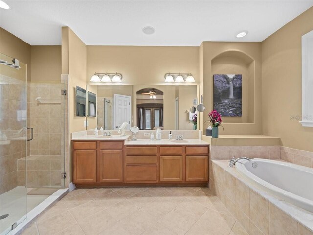bathroom with a garden tub, tile patterned flooring, a sink, a stall shower, and double vanity