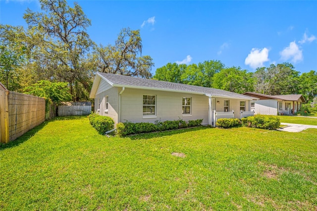 view of front of house with fence, a front lawn, and concrete block siding