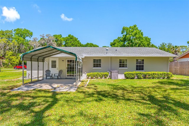 rear view of property featuring a detached carport, fence, a patio, stucco siding, and a yard