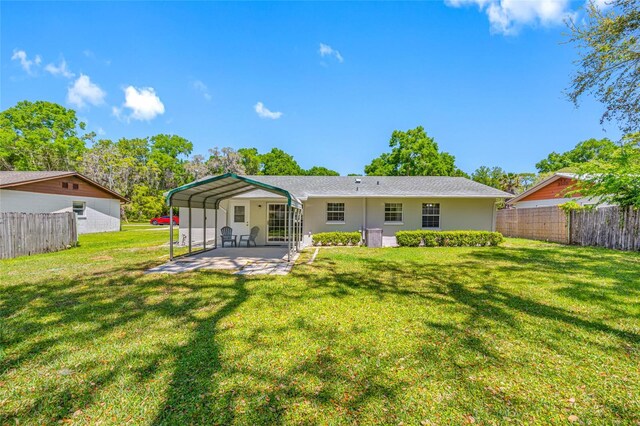 rear view of house with a lawn and fence