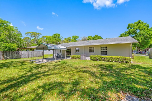 rear view of property featuring fence, central AC, a patio area, a lawn, and a carport