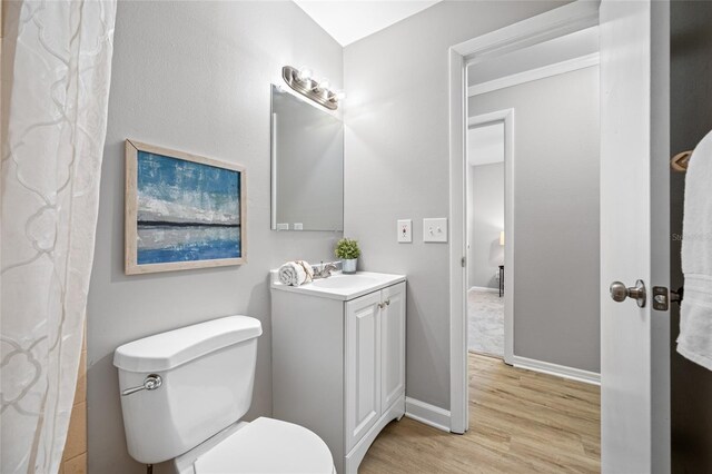 full bath featuring vanity, baseboards, wood finished floors, and toilet