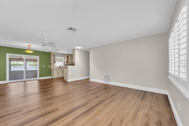 unfurnished living room with visible vents, ceiling fan, light wood-type flooring, and baseboards