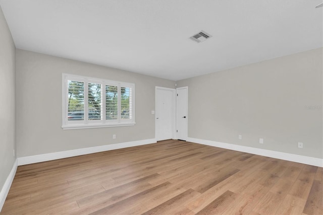 empty room featuring light wood-style flooring, baseboards, and visible vents