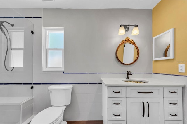 bathroom with toilet, tile walls, a tile shower, and vanity