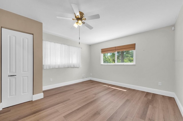 spare room with wood finished floors, ceiling fan, and baseboards