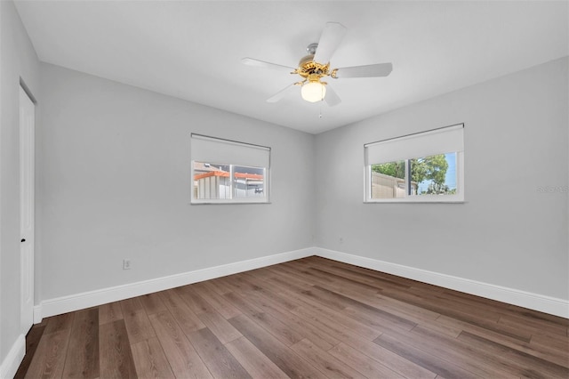 empty room featuring ceiling fan, baseboards, and wood finished floors