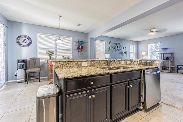 kitchen featuring stainless steel dishwasher, visible vents, light tile patterned flooring, a kitchen island with sink, and a sink