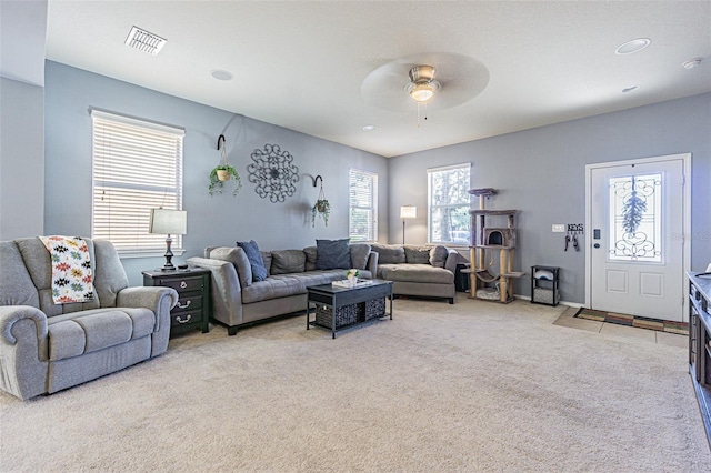 living room with light colored carpet, a ceiling fan, and visible vents