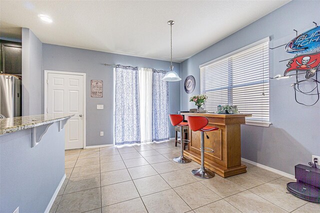 dining room with light tile patterned floors, baseboards, and a dry bar
