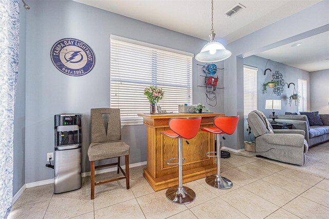 dining room featuring a bar, baseboards, visible vents, and plenty of natural light