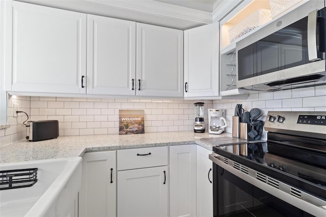 kitchen with appliances with stainless steel finishes, white cabinets, decorative backsplash, and light stone counters