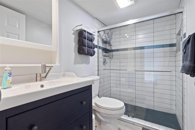 bathroom with vanity, a stall shower, toilet, and wood finished floors