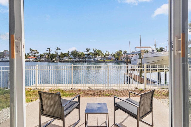 view of patio / terrace featuring a water view, fence, and a residential view