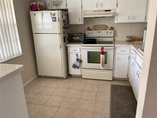 kitchen featuring under cabinet range hood, decorative backsplash, light countertops, and white appliances